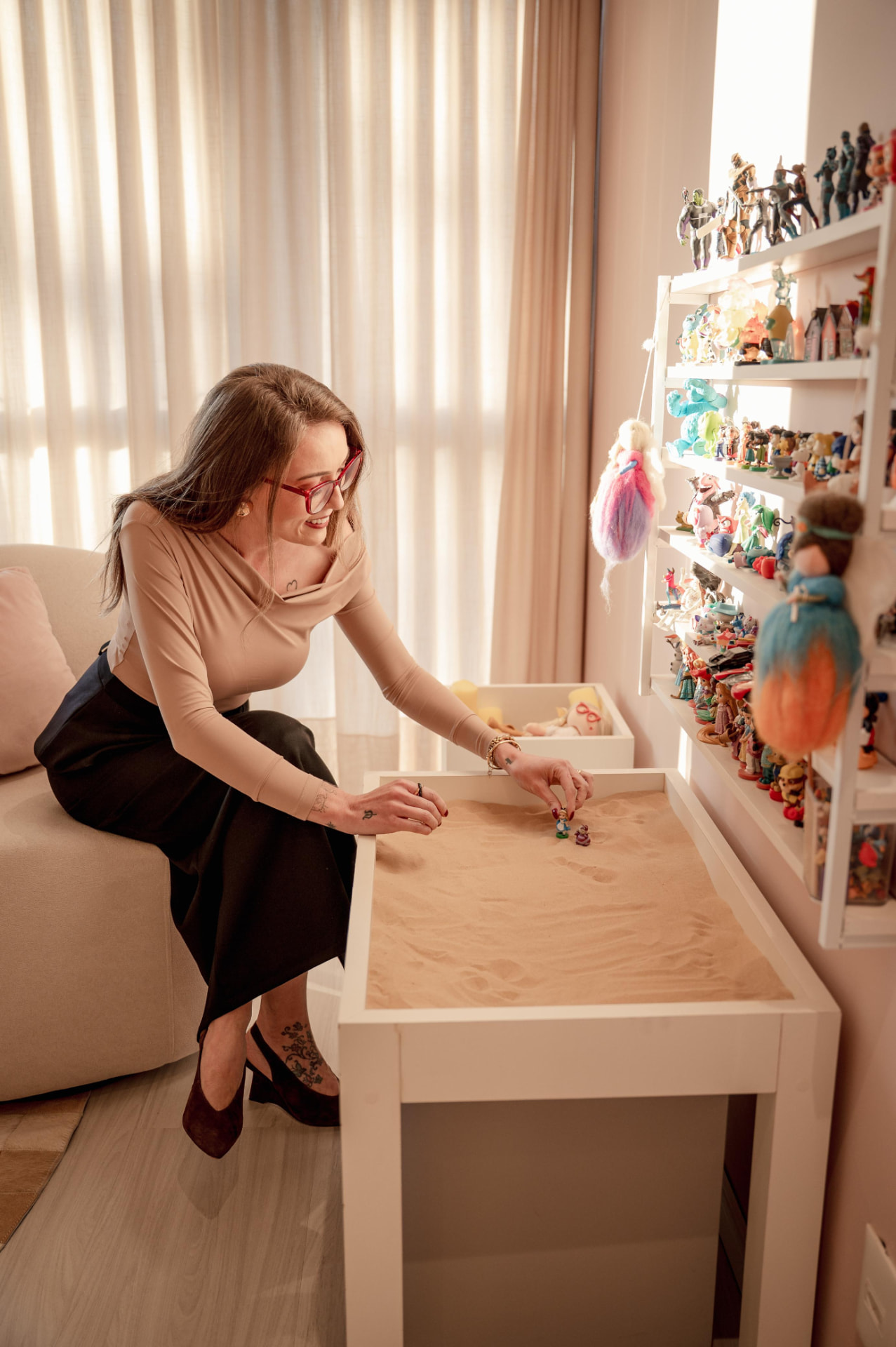 Evelise organizando miniaturas na caixa de areia durante o brincar terapêutico